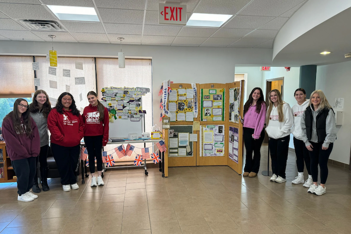 Students in Honors Course stand in front of display on Women's Suffrage Movement